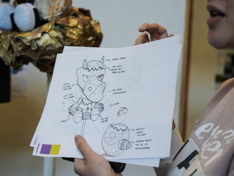 A student holds up a product sketch while giving a presentation.
