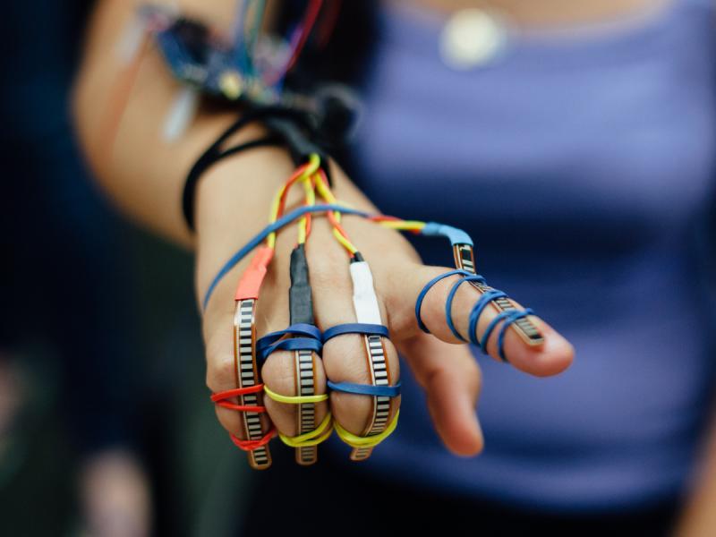 A student wears sensors on all her fingers, held on with rubber bands.