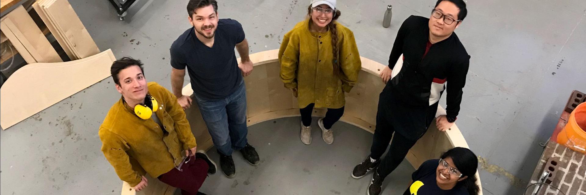 Students pose inside a gigantic wheel that they fabricated.