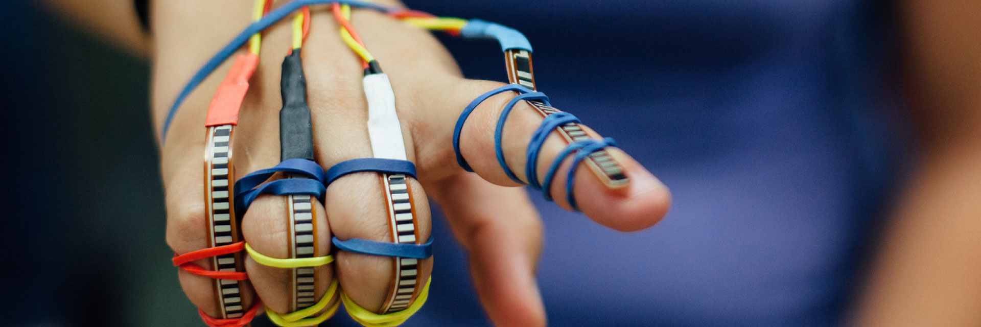 A student wears sensors on each of her fingers, held on by rubber bands.