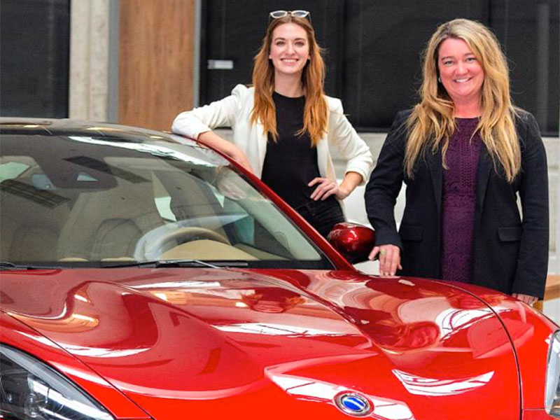 Industrial Design alumnae stand by a car.