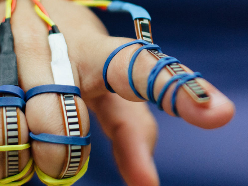 hand with blue wires and sensors wrapped around the fingers