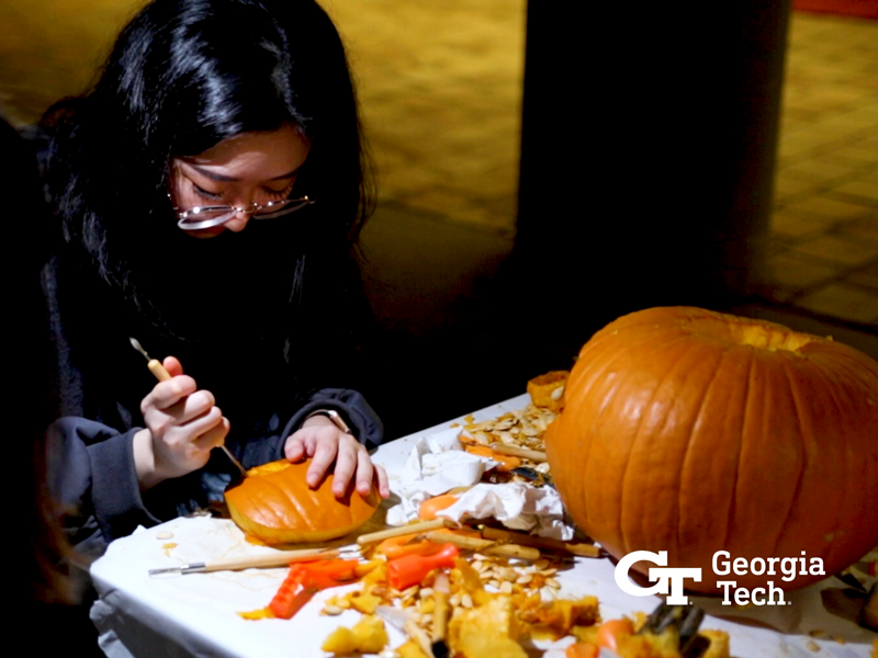 A student carving a pumpkin