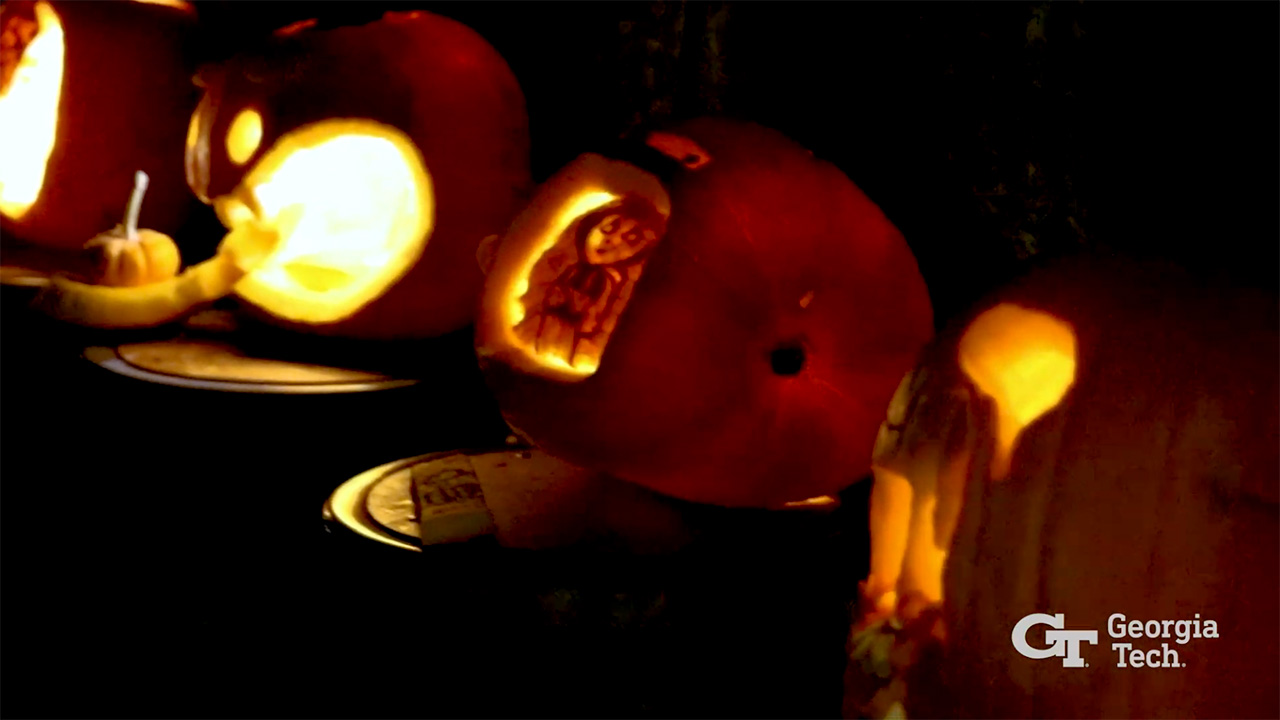 Video still of lit jack-o'-lanterns lined up on a table