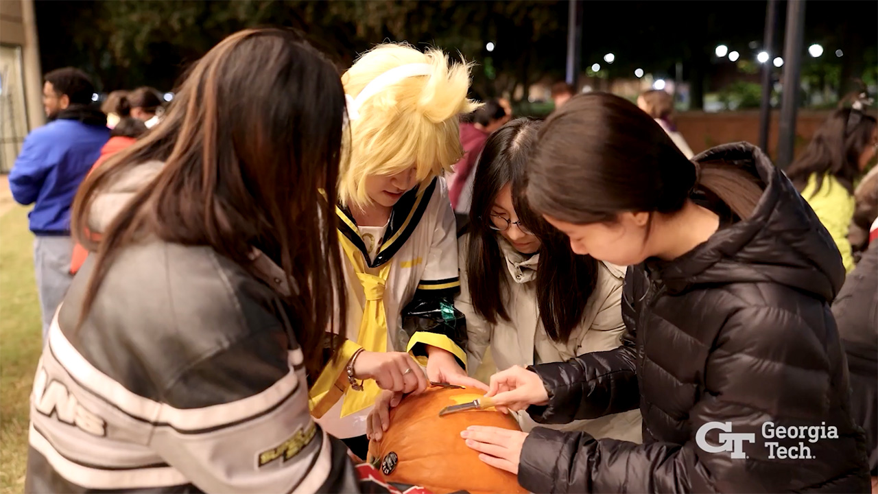 Video still of students carving a pumpkin