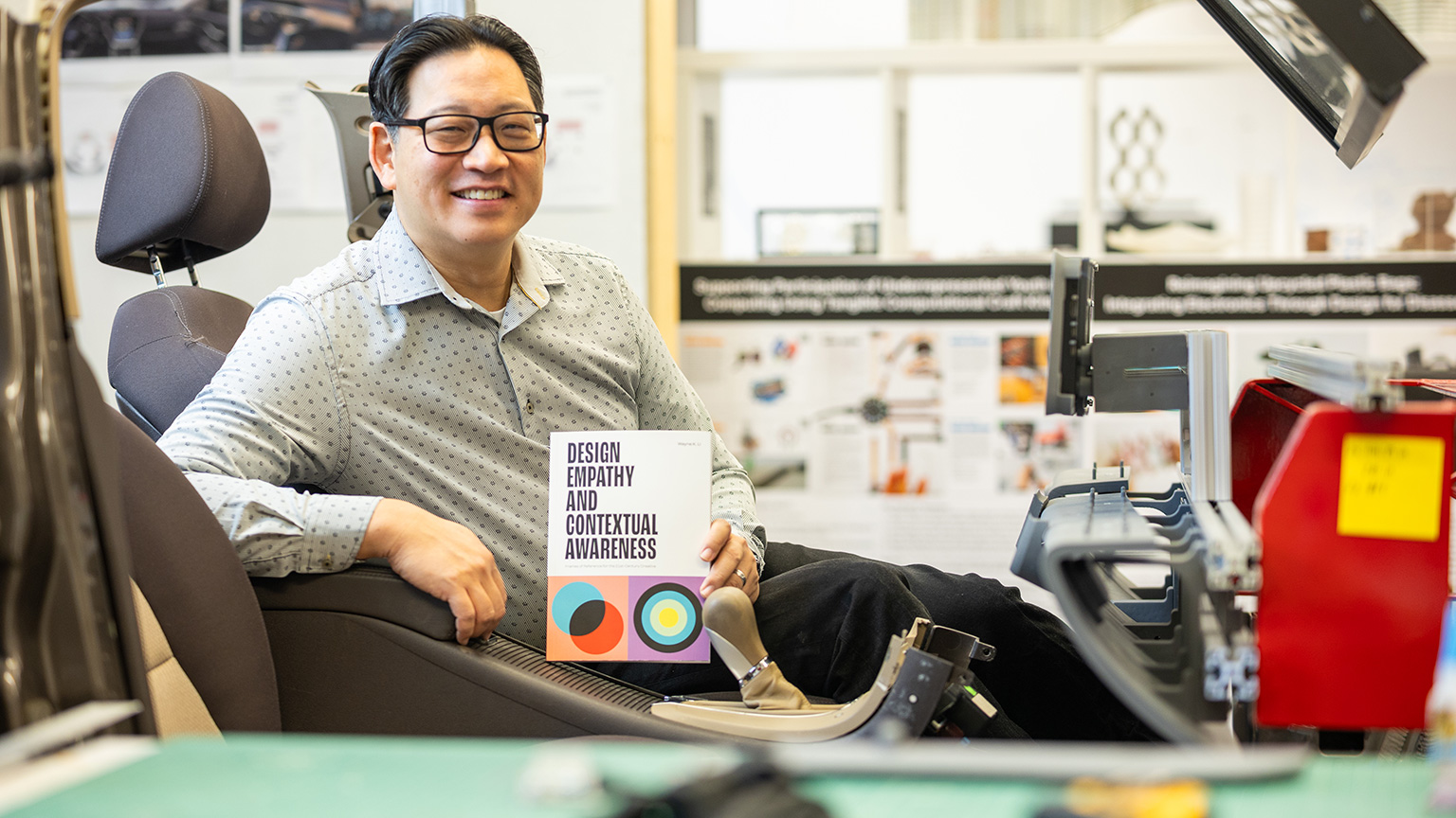 Wayne Li holds his textbook in the GM Human Machine Interaction lab. 
