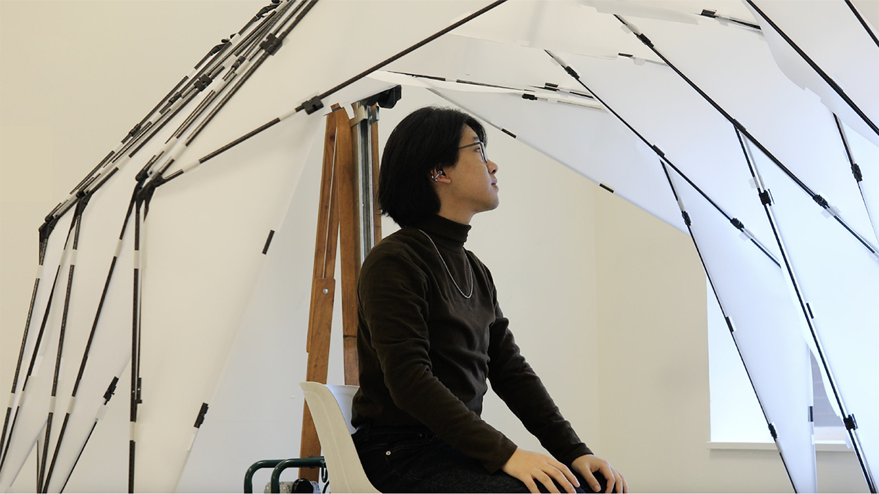 A student sits inside a robotic environment.